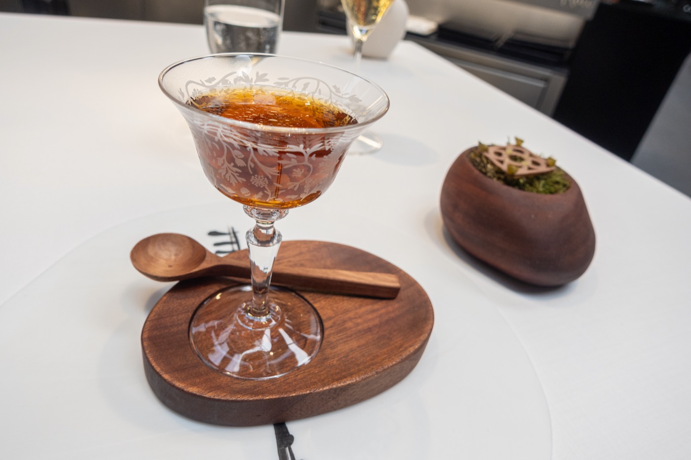 ‘Escudella amb Pilota’. The broth in its glass cup, with the pilota under moss beside it.