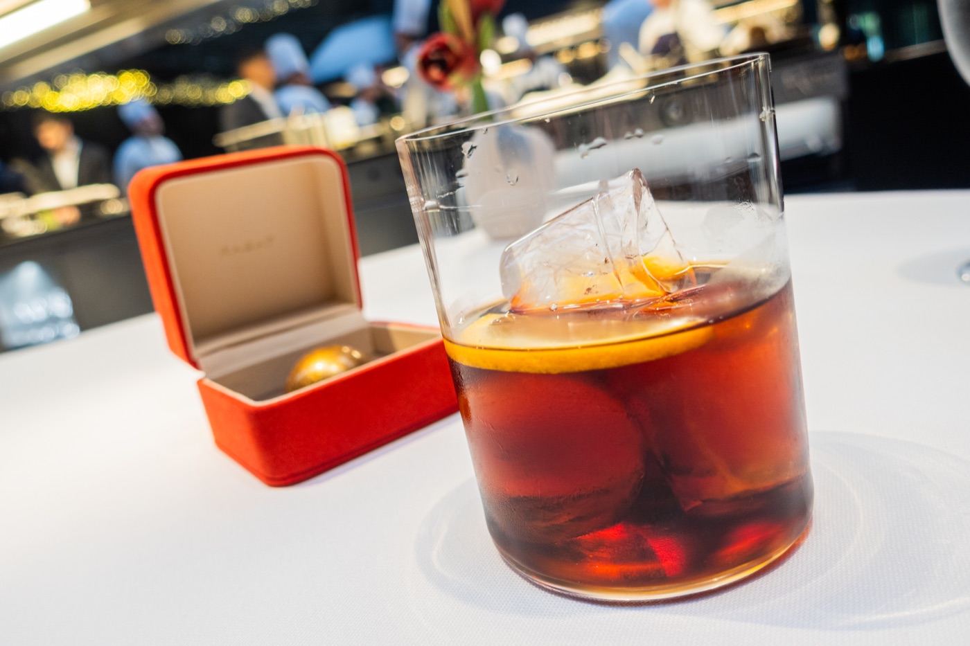 The Jewel. For you. Beside an amber drink with a clear ice cube and an orange slice.