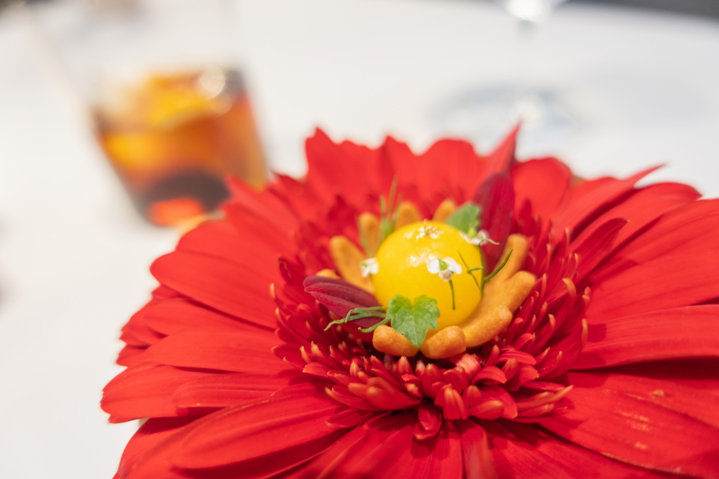 Orange Flower. Citrus. A red flower holding a bright citrus sphere, on a carved wooden stone.
