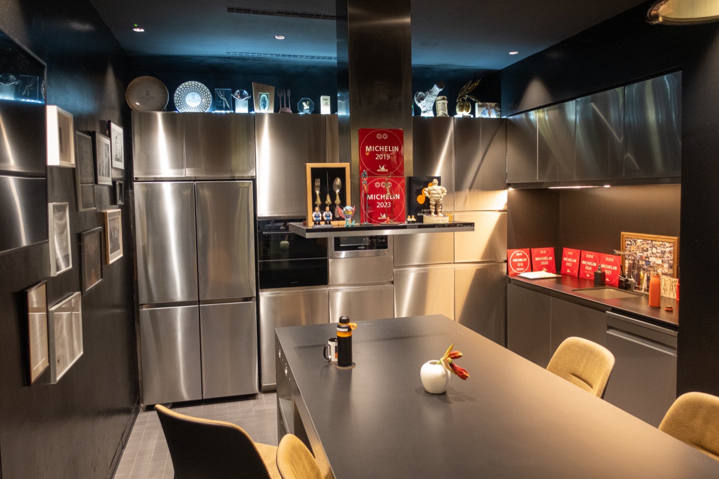 A room beside the kitchen, with steel fridges and a long table.